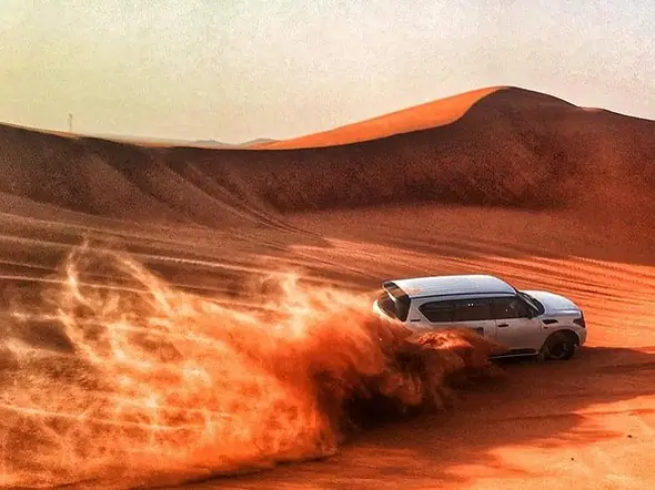 4x4 blanco levantando arena roja en una duna cerca de Merzouga