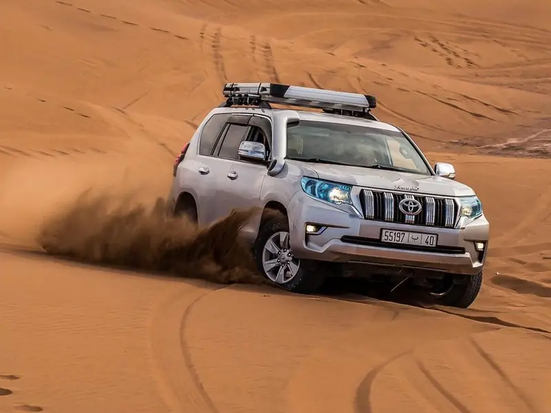 Silver 4x4 driving through the Merzouga dunes
